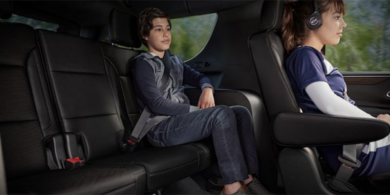 interior of 2024 chevy tahoe side profile image of captin chairs and back seat with a young boy and girl as passengers